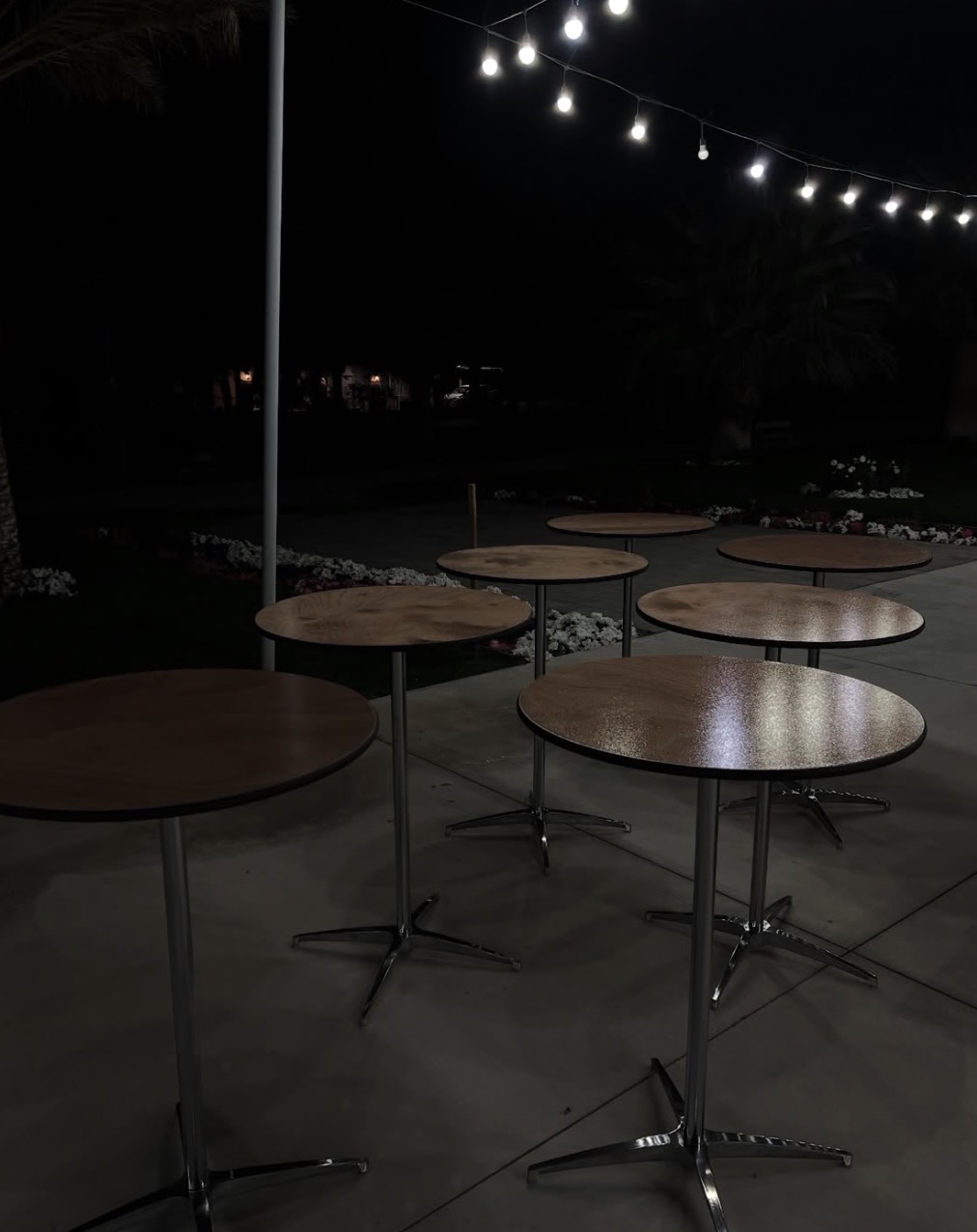 Cocktail tables lit by string lights at an evening event