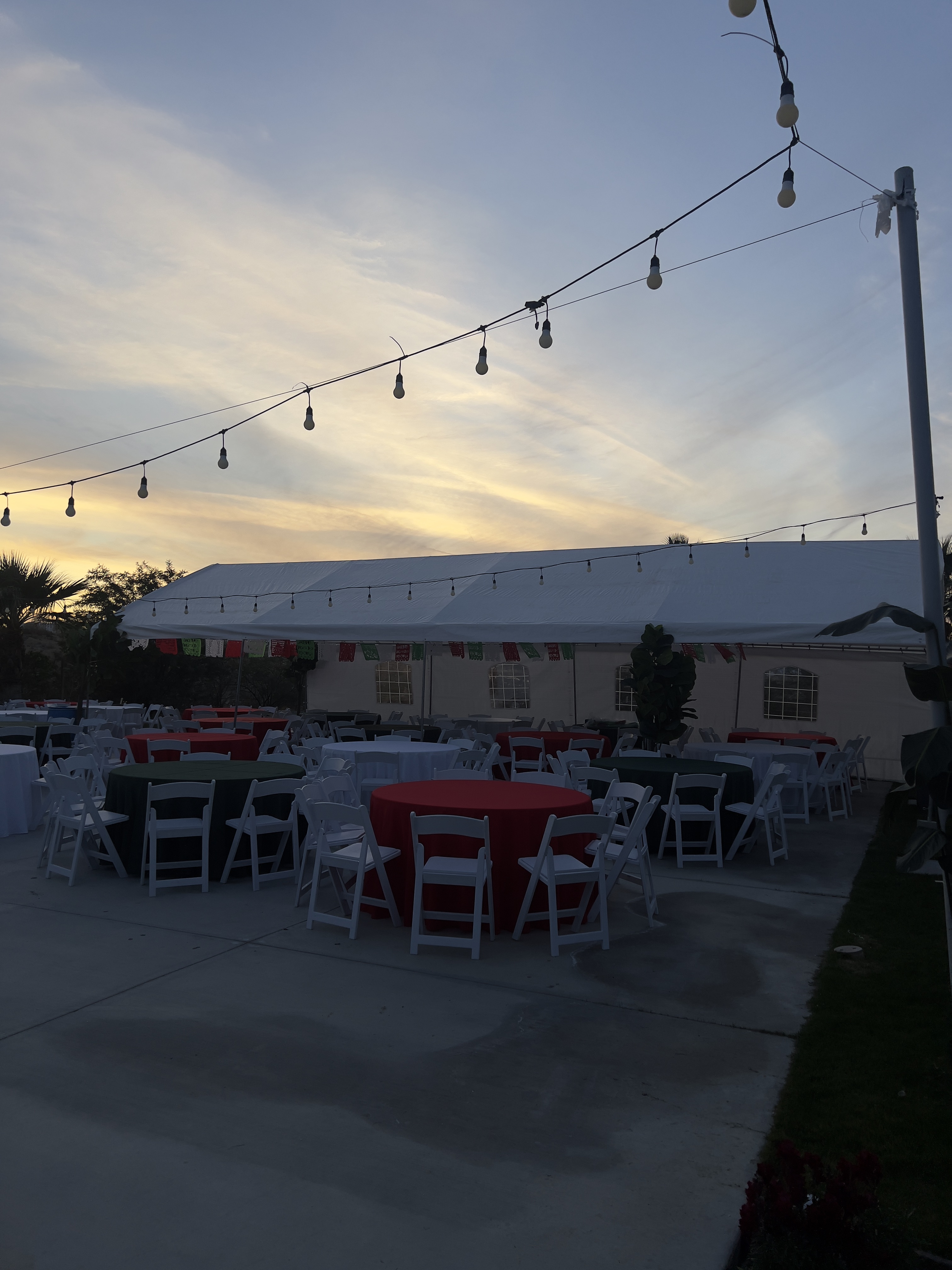 20x40 canopy with round tables, resin chairs and colored linens at sunset